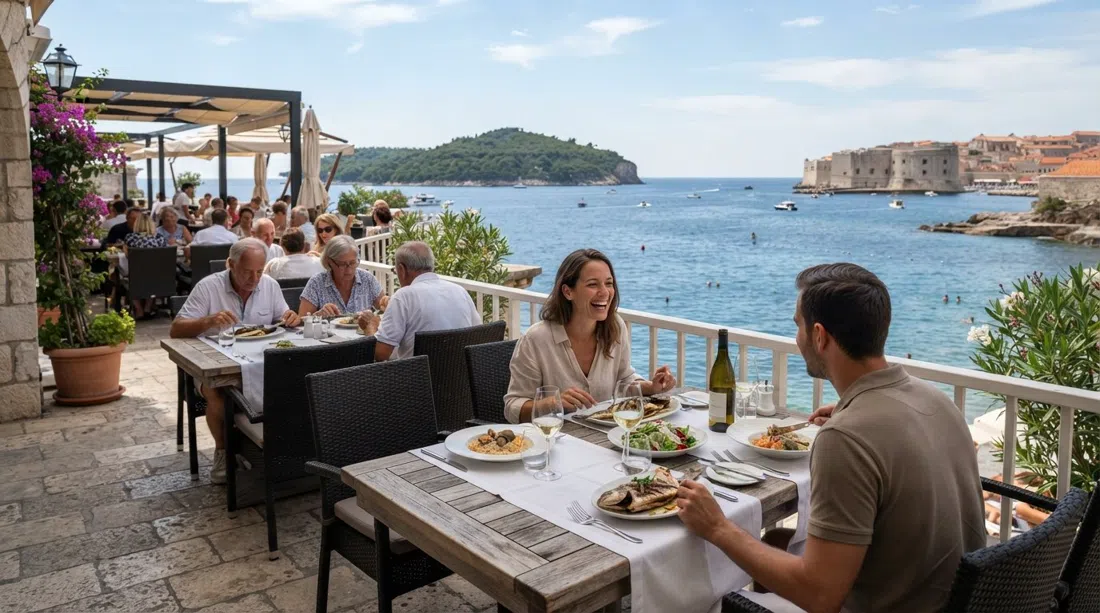 the shorefront terrace at Prora, Hotel Excelsior, with Lokrum visible beyond the water and a fish-forward summer lunch setting